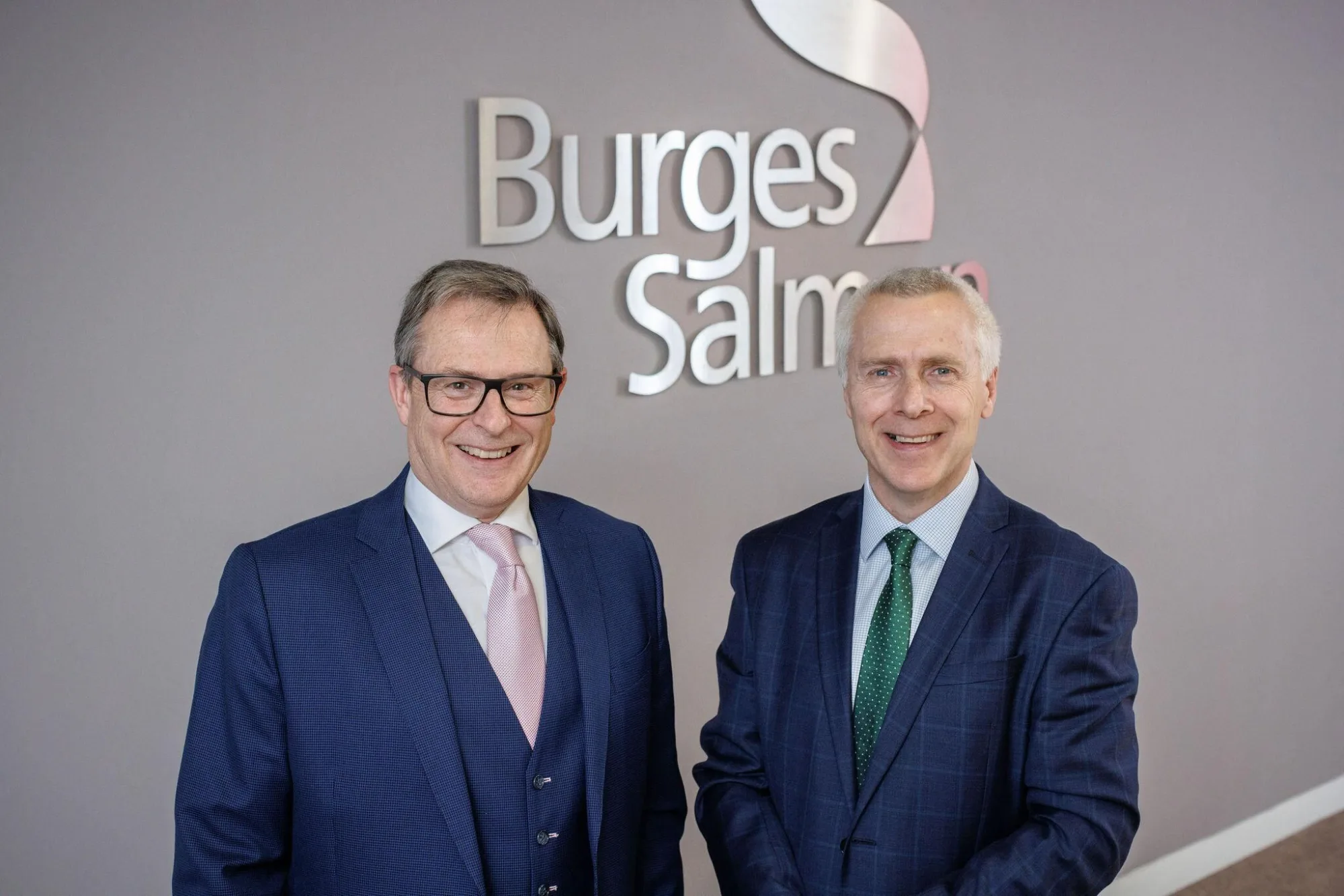 Burges Salmon partners in front of the firm's logo