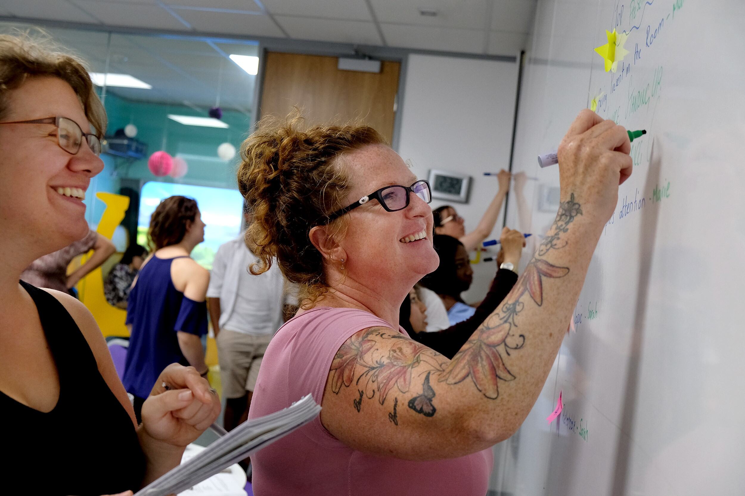 Happy team members collaborating at a workshop whiteboard